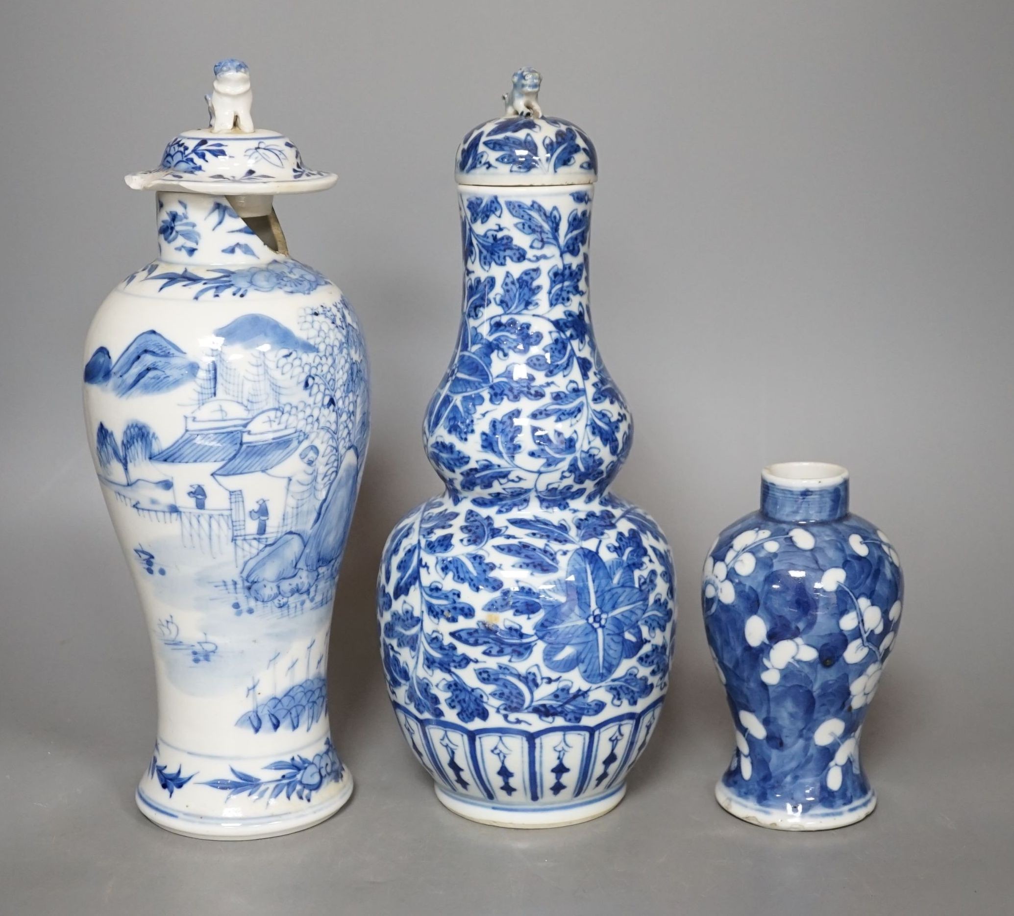 A Chinese double gourd vase and cover, a similar vase and cover and a prunus vase, all 19th century, tallest 28 cms high.